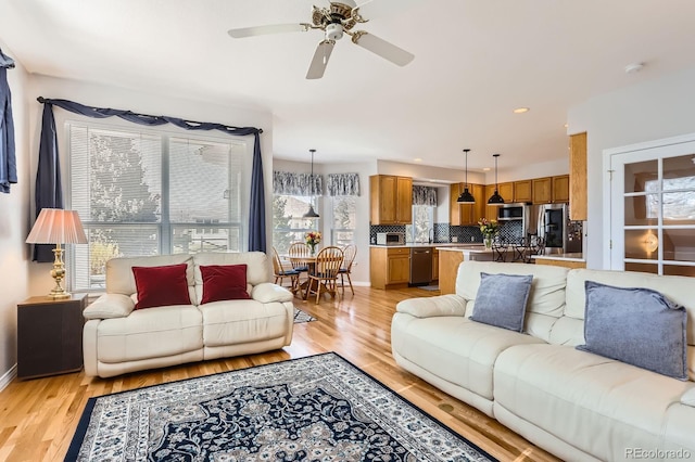 living area featuring light wood-type flooring, baseboards, a ceiling fan, and recessed lighting