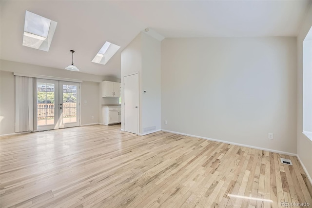 1758 S Ensenada St, Aurora, CO 80017 - unfurnished living room featuring light wood finished floors, a skylight, vaulted ceiling, french doors, and baseboards