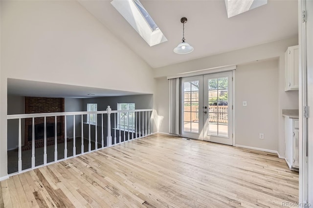 1758 S Ensenada St, Aurora, CO 80017 - unfurnished living room featuring a skylight, light wood finished floors, high vaulted ceiling, and french doors
