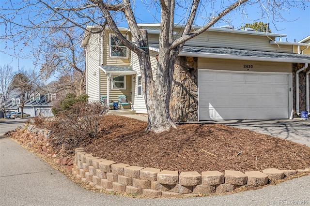 view of front of home featuring stone siding, concrete driveway, and a shingled roof