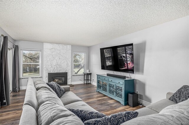 living area featuring a fireplace, baseboards, dark wood finished floors, and a textured ceiling