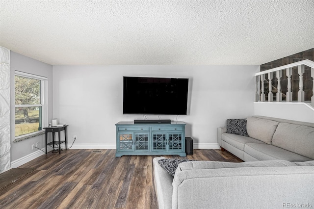 living room with dark wood-style flooring, a textured ceiling, and baseboards