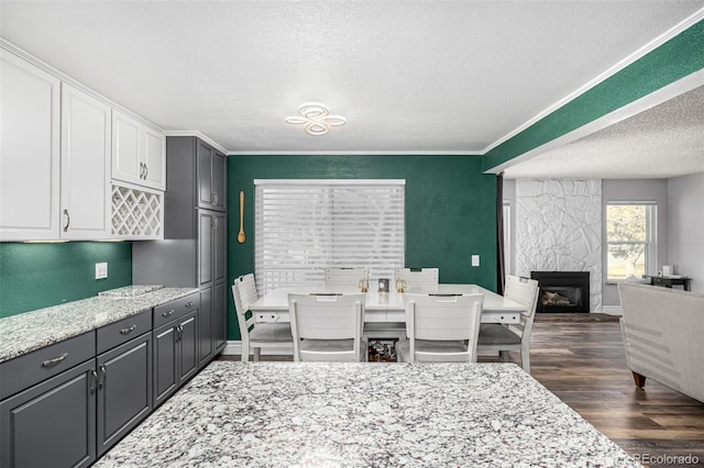 dining room with crown molding, a textured ceiling, dark wood-style flooring, and a high end fireplace