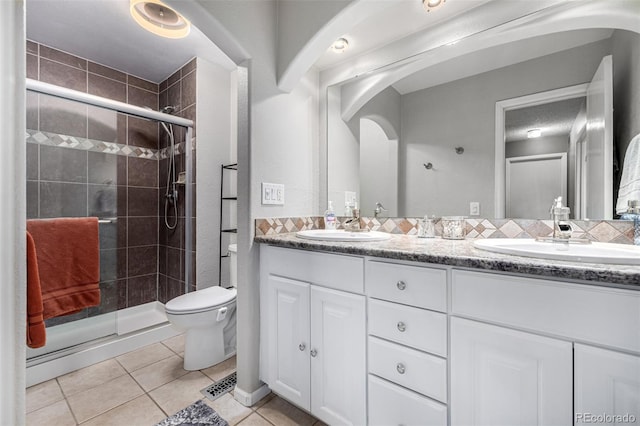 bathroom featuring toilet, a shower stall, a sink, and tile patterned floors