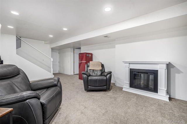 carpeted living area with a glass covered fireplace, visible vents, and recessed lighting