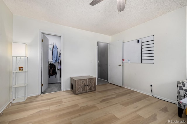 bedroom featuring a textured ceiling, wood finished floors, a ceiling fan, and baseboards