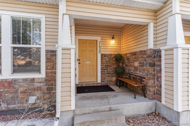 view of exterior entry featuring a porch and stone siding