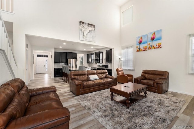 living room featuring a towering ceiling and light hardwood / wood-style flooring