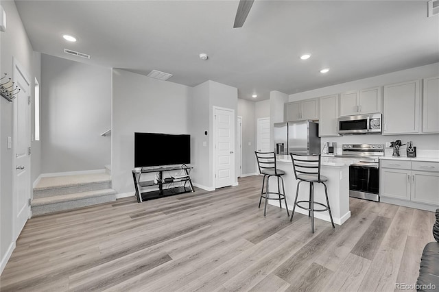 620 Apache Trl Unit A1, Ault, CO 80610 - kitchen with appliances with stainless steel finishes, a kitchen island, light wood finished floors, a breakfast bar area, and recessed lighting