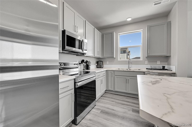 620 Apache Trl Unit A1, Ault, CO 80610 - kitchen featuring appliances with stainless steel finishes, gray cabinets, light stone countertops, and light wood-style flooring