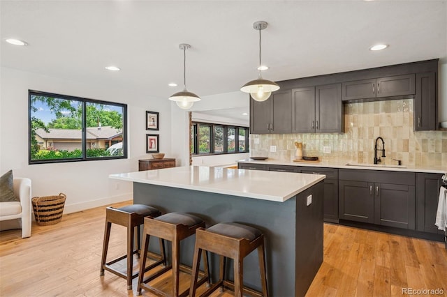 4634 W Tufts Cir, Denver, CO 80236 - kitchen featuring light wood-style flooring, light countertops, a breakfast bar area, a center island, and recessed lighting