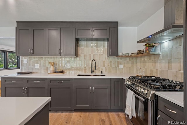4634 W Tufts Cir, Denver, CO 80236 - kitchen with wall chimney exhaust hood, stainless steel range with gas cooktop, light countertops, decorative backsplash, and light wood finished floors