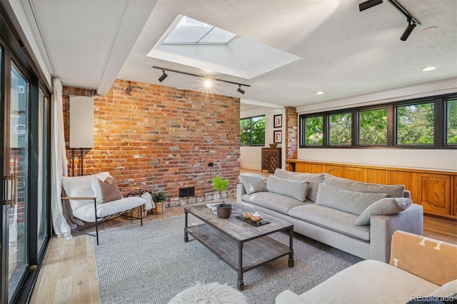 4634 W Tufts Cir, Denver, CO 80236 - living room with track lighting, light wood finished floors, a skylight, brick wall, and lofted ceiling
