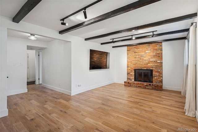 4634 W Tufts Cir, Denver, CO 80236 - unfurnished living room with rail lighting, beamed ceiling, light wood-type flooring, and a fireplace