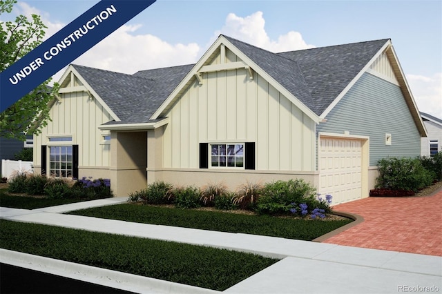 21885 E 51st Dr, Aurora, CO 80019 - view of front facade with board and batten siding, roof with shingles, a garage, and decorative driveway