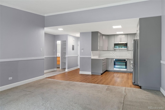 kitchen featuring light hardwood / wood-style flooring, gray cabinets, stainless steel appliances, and tasteful backsplash