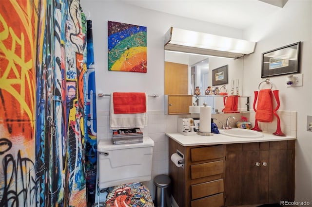 bathroom featuring vanity, tile walls, and toilet