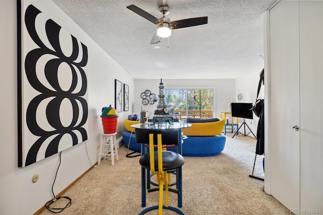 dining area featuring ceiling fan, light colored carpet, and a textured ceiling