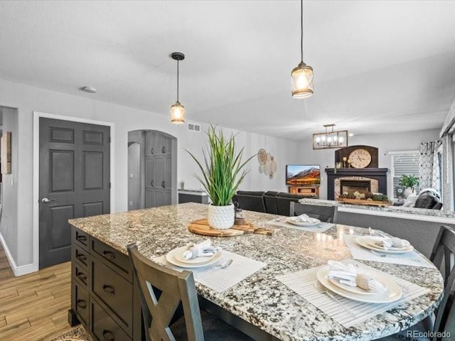 dining space with light wood finished floors, visible vents, arched walkways, baseboards, and a fireplace