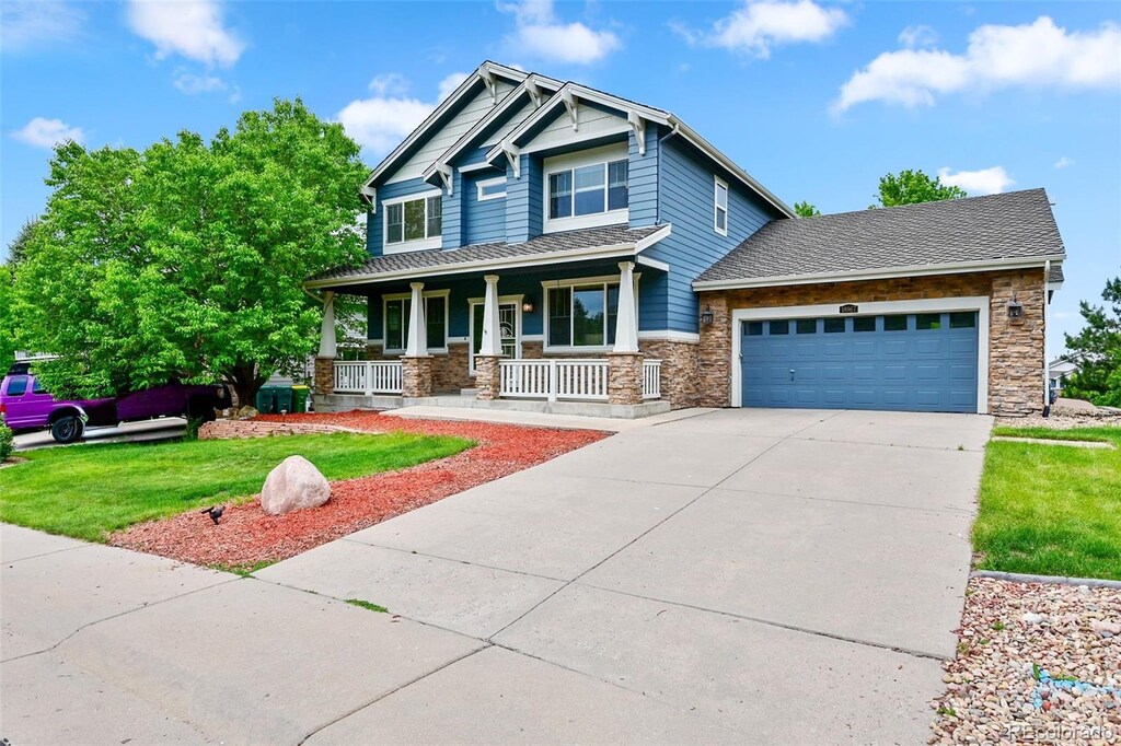 18967 W 54th Ln, Golden, CO 80403 - craftsman inspired home featuring covered porch, stone siding, concrete driveway, an attached garage, and a front lawn