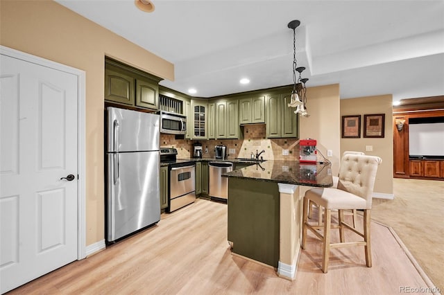 18967 W 54th Ln, Golden, CO 80403 - kitchen with green cabinetry, appliances with stainless steel finishes, a peninsula, a kitchen bar, and recessed lighting