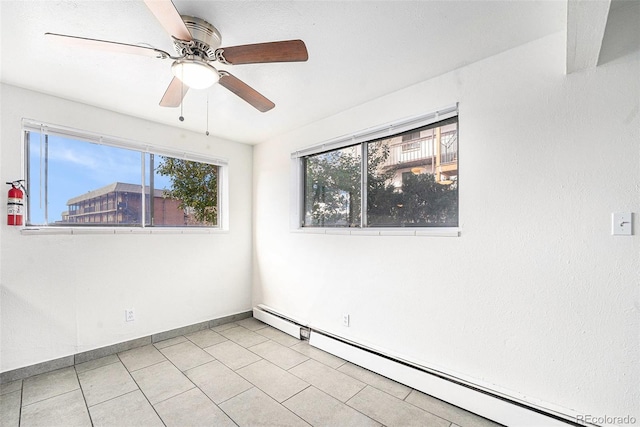 tiled empty room with ceiling fan and baseboard heating