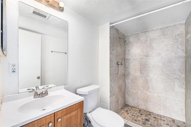 bathroom featuring tiled shower, vanity, and toilet