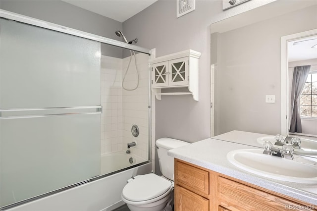 full bathroom with combined bath / shower with glass door, vanity, and toilet