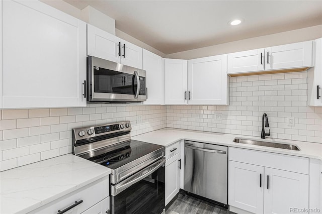 kitchen with stainless steel appliances, white cabinetry, sink, and backsplash