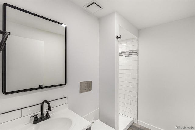 bathroom with hardwood / wood-style flooring, vanity, toilet, and tiled shower