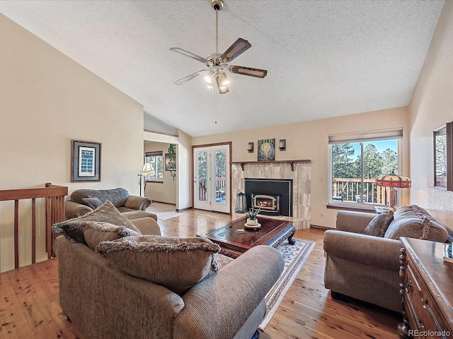 living room with light wood-type flooring, a textured ceiling, ceiling fan, and high vaulted ceiling