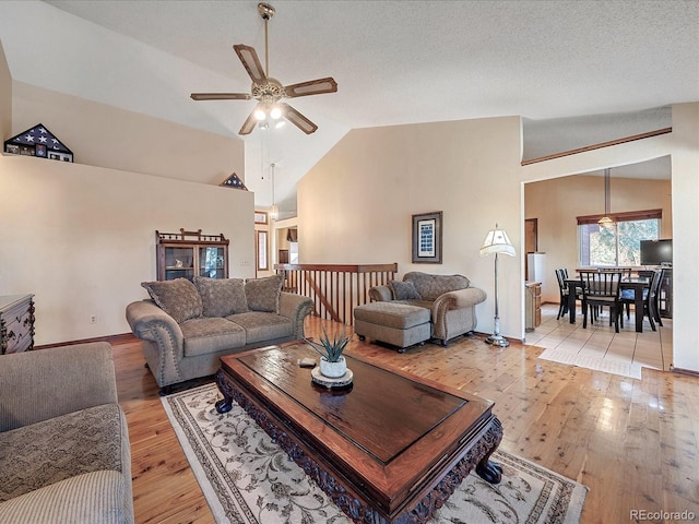 living room with high vaulted ceiling, ceiling fan, a textured ceiling, and light hardwood / wood-style floors