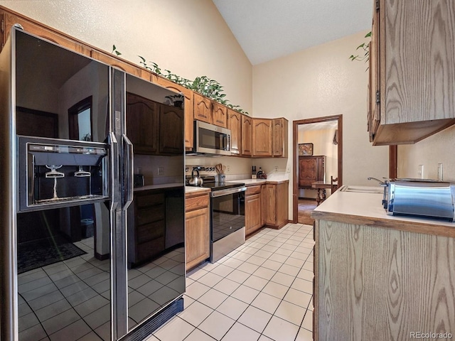 kitchen with light tile patterned floors, vaulted ceiling, sink, and appliances with stainless steel finishes