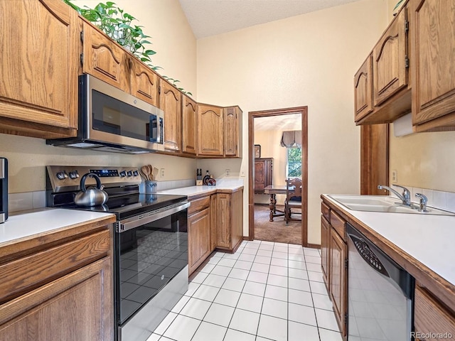 kitchen featuring a textured ceiling, appliances with stainless steel finishes, light tile patterned floors, and sink