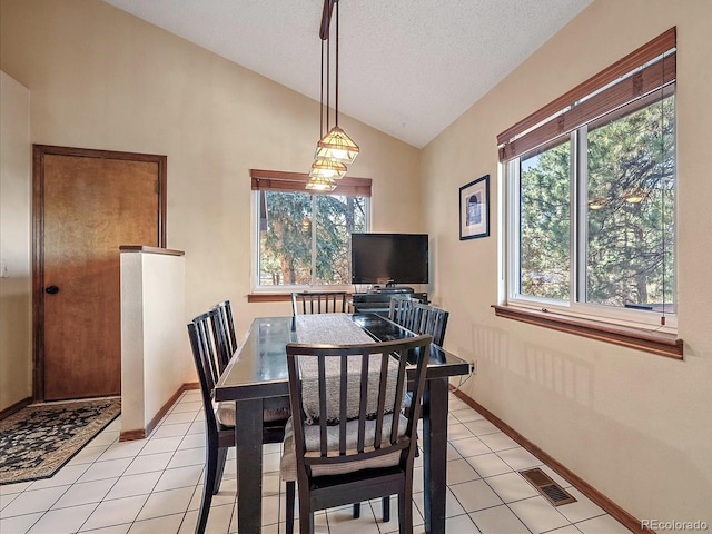 tiled dining room featuring a textured ceiling and lofted ceiling