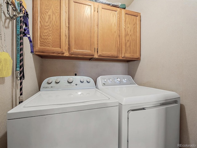 laundry room featuring separate washer and dryer and cabinets