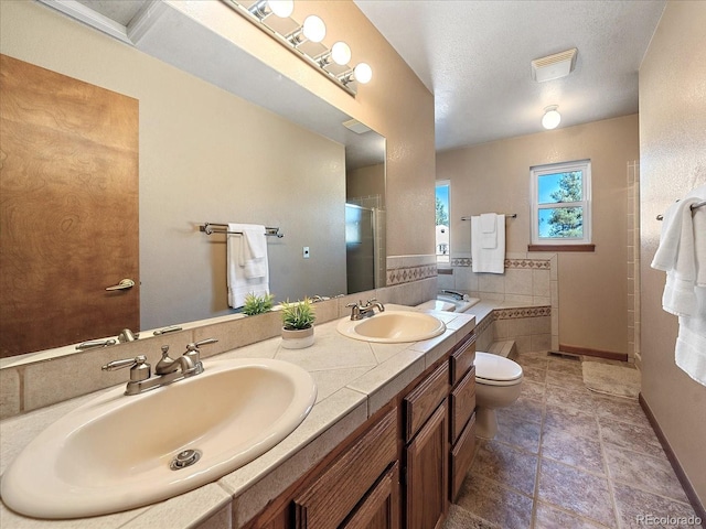 bathroom with a textured ceiling, vanity, a shower with shower door, tile patterned floors, and toilet