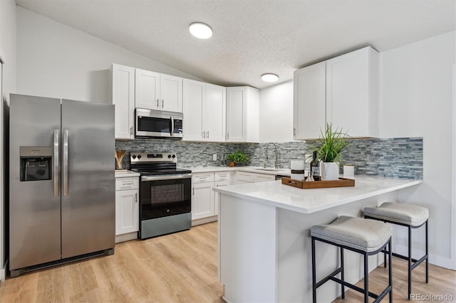 1418 5th St, Fort Lupton, CO 80621 - kitchen with stainless steel appliances, white cabinetry, a peninsula, a kitchen breakfast bar, and light countertops