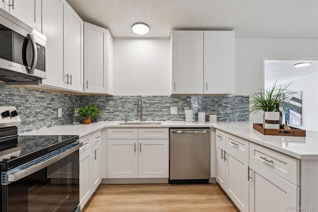 1418 5th St, Fort Lupton, CO 80621 - kitchen with appliances with stainless steel finishes, light countertops, white cabinets, light wood-style flooring, and a textured ceiling