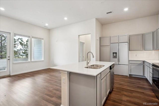 kitchen featuring refrigerator with ice dispenser, sink, dishwasher, gray cabinetry, and a center island with sink