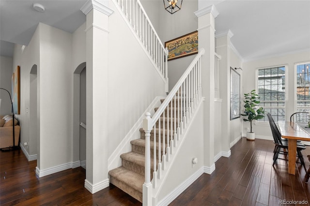 stairway with arched walkways, baseboards, and wood finished floors