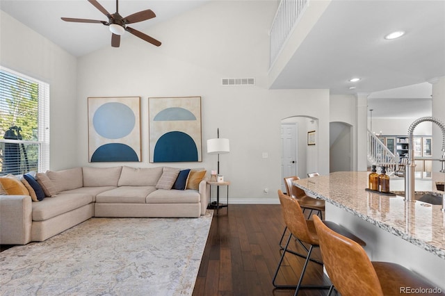 living area with stairway, baseboards, visible vents, ceiling fan, and dark wood-type flooring