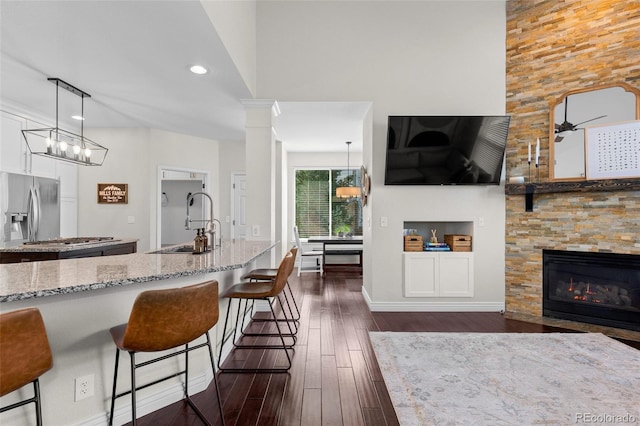 kitchen with a kitchen bar, dark wood-type flooring, a sink, stainless steel appliances, and light stone countertops