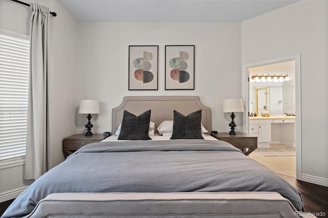 bedroom featuring baseboards, wood finished floors, and ensuite bathroom