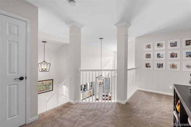 hall with a notable chandelier, baseboards, ornate columns, and carpet floors