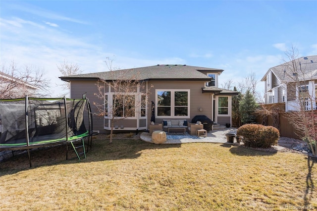 back of property featuring a lawn, a trampoline, fence, an outdoor hangout area, and a patio area