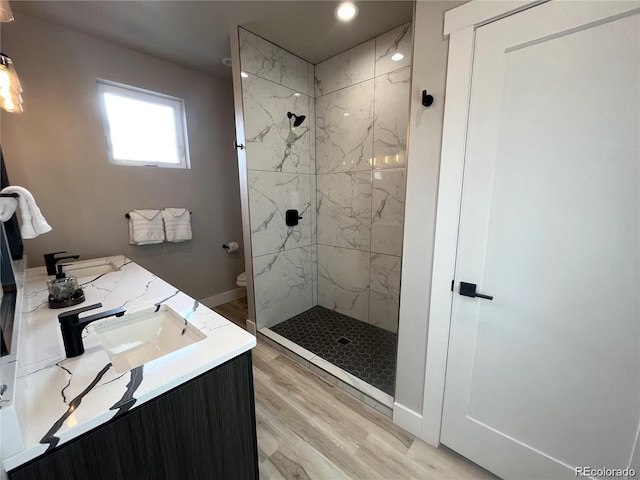 bathroom featuring vanity, toilet, wood-type flooring, and a tile shower