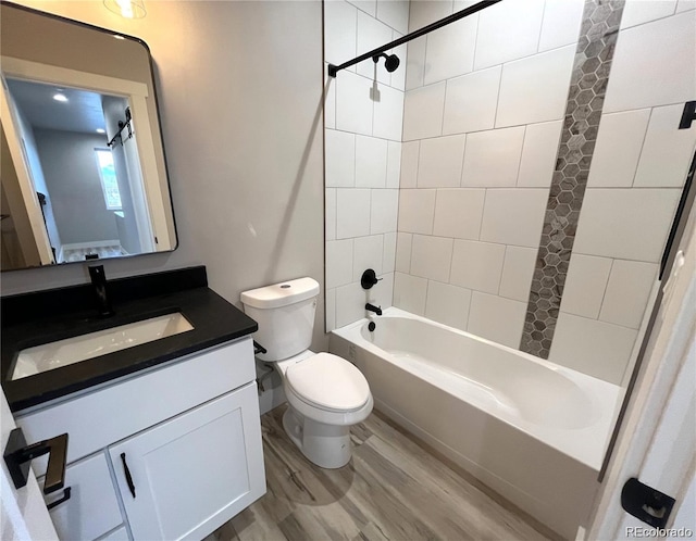 full bathroom with tiled shower / bath, toilet, vanity, and hardwood / wood-style flooring