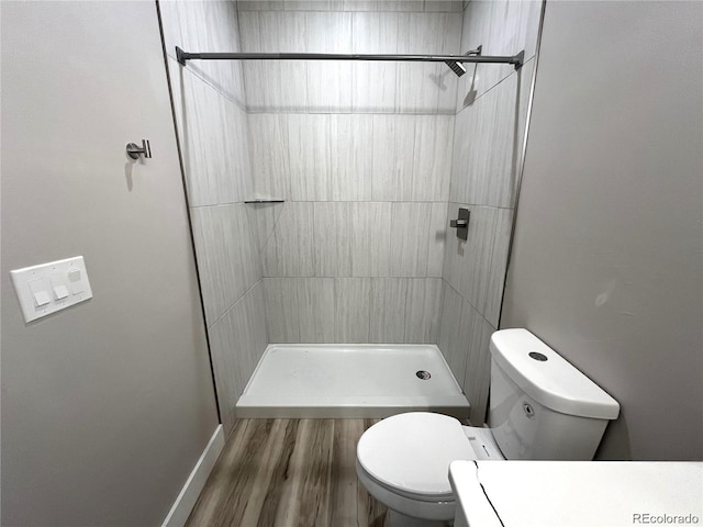 bathroom featuring tiled shower, vanity, wood-type flooring, and toilet