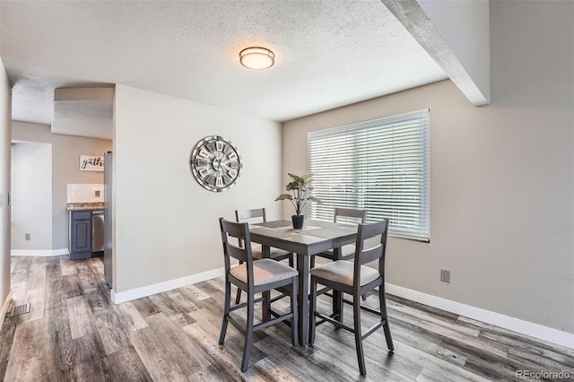 dining space featuring a textured ceiling and hardwood / wood-style flooring